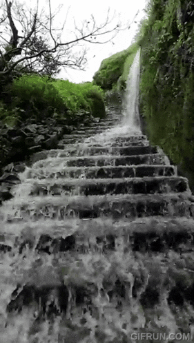 a waterfall is flowing down a set of stone stairs