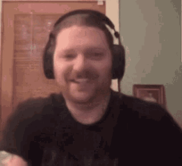 a man wearing headphones is smiling in front of a door .