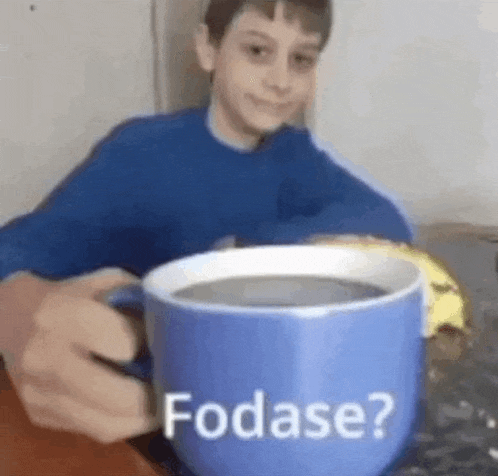 a young boy is holding a blue cup of coffee .
