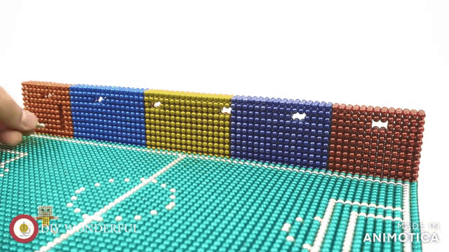 a row of colorful magnets are lined up on a green surface