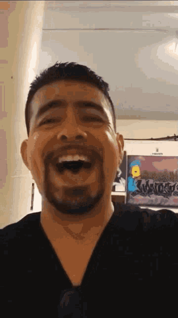 a man with a beard is laughing in front of a wall with graffiti on it