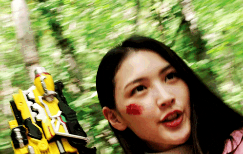 a woman with a red spot on her face is holding a yellow toy