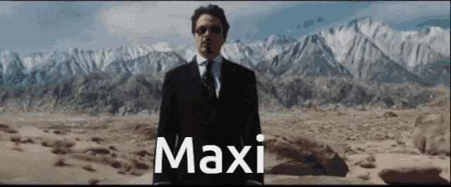 a man in a suit and tie is standing in front of a mountain and the word maxi is on the bottom