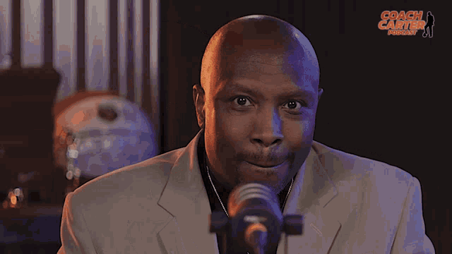a man stands in front of a microphone with the words coach carter podcast on the bottom
