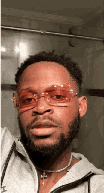 a man wearing sunglasses and a necklace with a cross on it