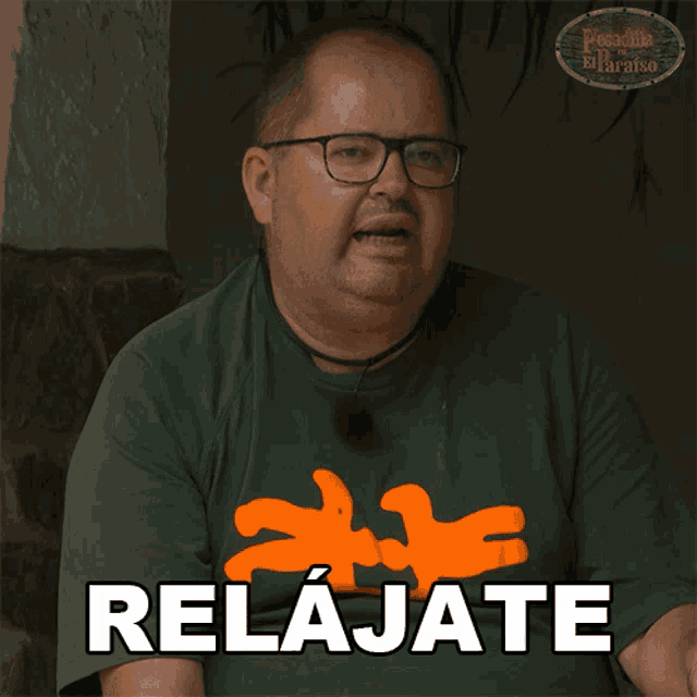 a man wearing glasses and a green shirt has the word relajate on his shirt