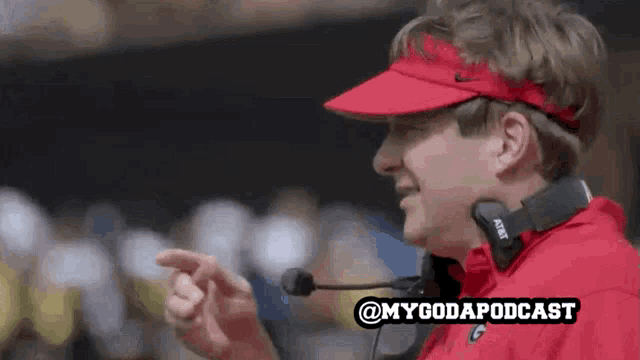 a man wearing a red visor and headphones with the words @mygodapodcast written below him