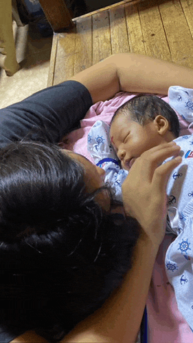 a woman is holding a baby who is wearing a blue anchor outfit