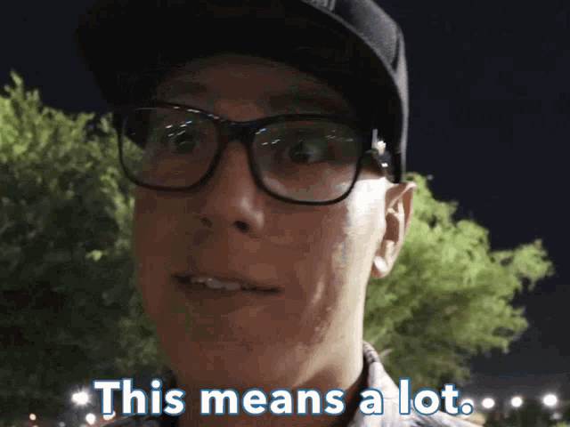 a man wearing glasses and a hat says this means a lot in blue letters