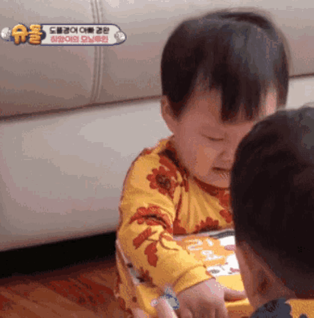 a baby in a yellow shirt is playing with another child