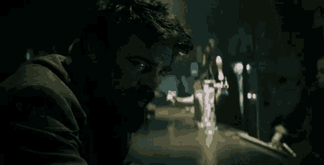 a man with a beard is sitting at a bar in a dark room