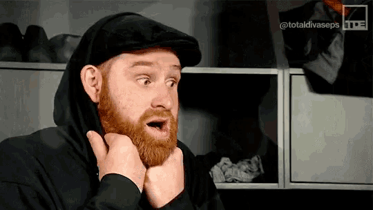 a man with a beard is wearing a black hat and a hoodie .