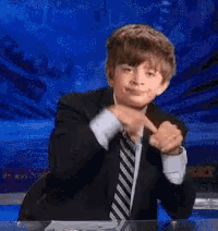 a young boy in a suit and tie is pointing