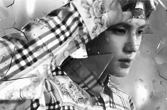 a black and white photo of a man in a plaid shirt standing in front of a broken glass wall .
