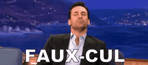 a man in a suit and tie is sitting in front of a screen that says faux-cul
