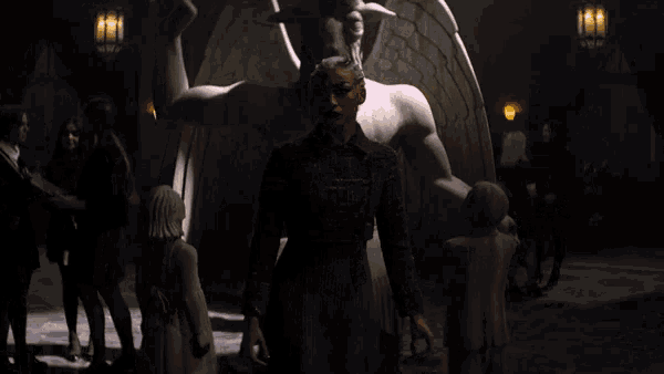 a woman with horns stands in front of a statue of an angel