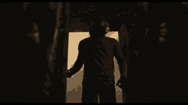 a man wearing a gas mask is standing in a dark room