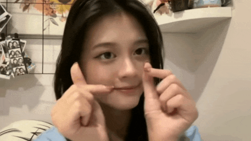 a girl is making a funny face with her fingers in front of her face