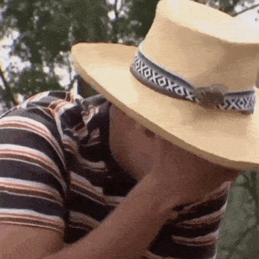 a man wearing a striped shirt and a hat with xoxox on it