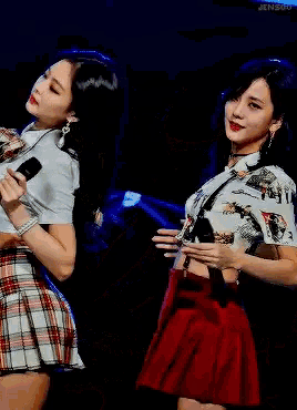 two women are standing next to each other and one has a microphone in her hand