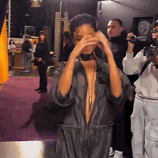 a woman wearing a choker covering her face while a man takes a picture of her