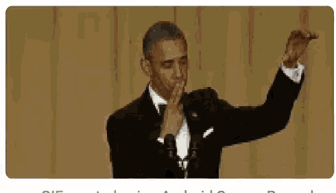 barack obama is wearing a tuxedo and bow tie while giving a speech in front of a microphone .