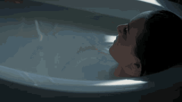a woman laying in a bathtub looking up
