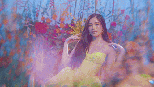 a woman in a bright yellow dress is standing in front of a field of flowers