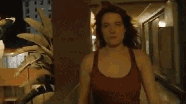 a woman in a tank top stands in a hallway