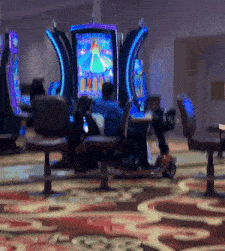 a man sits at a table in front of a slot machine with a princess on the screen