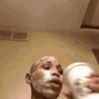 a man with shaving cream on his face is holding a cup of coffee .