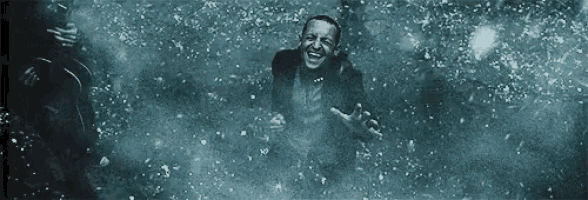 a man in a suit and tie is standing in a pool of water and laughing .
