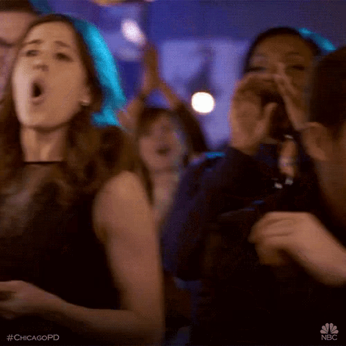 a group of people are dancing in a club and one of them is holding a cell phone in her hand .