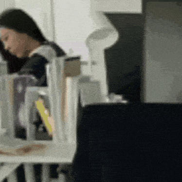 a blurry picture of a woman sitting at a table with a lamp .