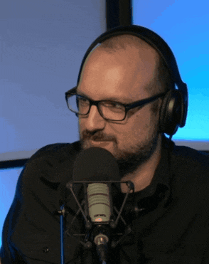 a man wearing glasses and headphones is talking into a rode microphone