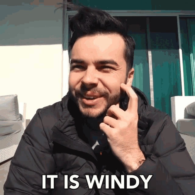 a man talking on a cell phone with the words " it is windy " above him