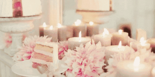 a table with candles and flowers and a piece of cake on it .