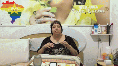 a woman sits on a bed in front of a web diva poster