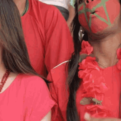 a woman with her face painted red and green is wearing a red dress
