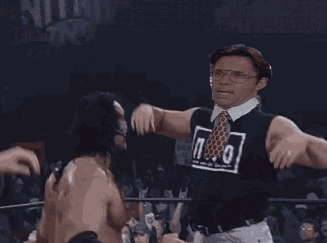 a wrestler with long hair is standing in a ring with his arm outstretched