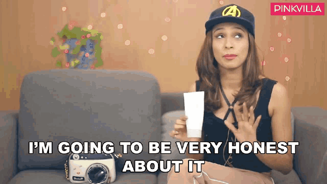 a woman sitting on a couch holding a piece of paper that says i 'm going to be very honest about