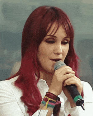 a woman with red hair holds a microphone in her hand