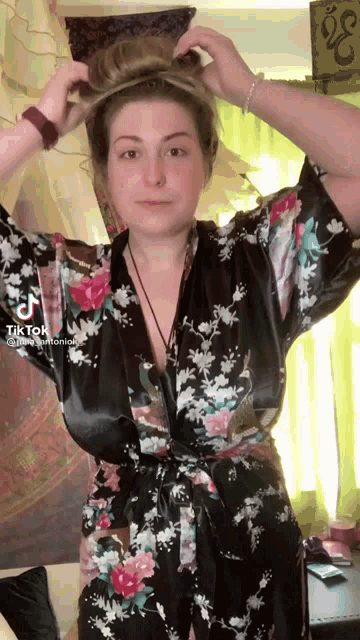 a woman in a floral robe has tiktok written on the bottom of her screen