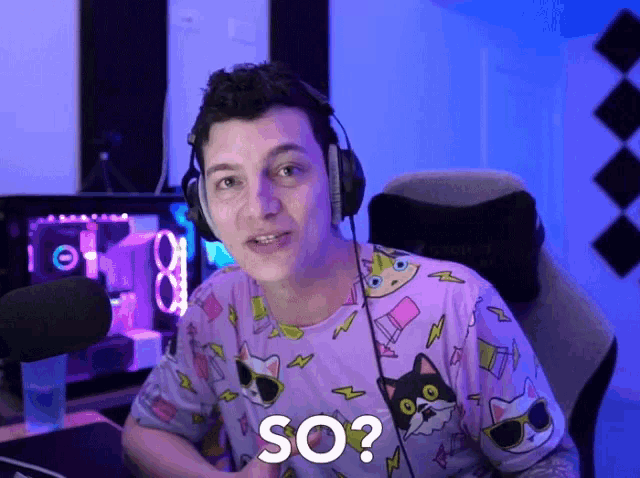 a man wearing headphones and a shirt that has cats on it says so