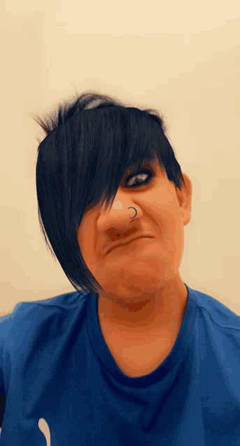 a person with a nose ring is wearing a blue shirt and making a funny face