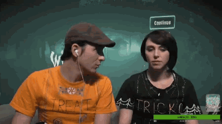 a man wearing a trick or treat shirt looks at a woman wearing a black trick or treat shirt