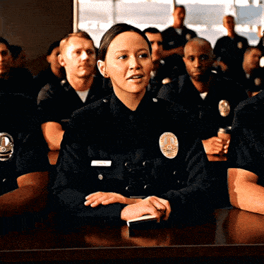 a group of police officers are sitting at a table and one of them has a name tag that says ' open ' on it