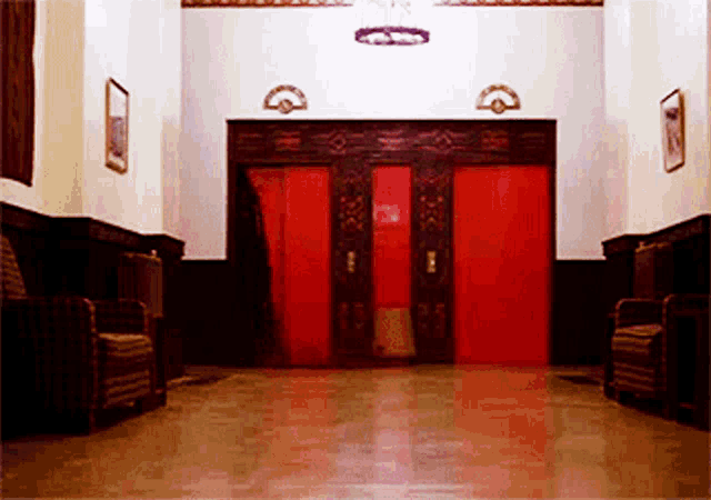 a hallway with chairs and a red door