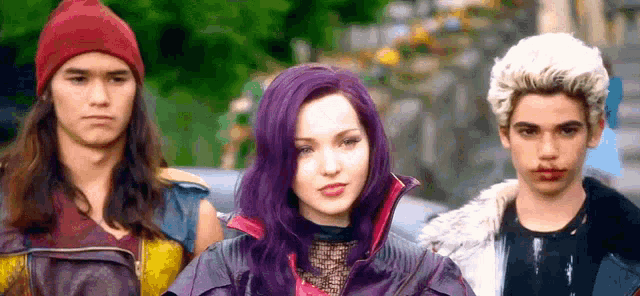 a woman with purple hair is standing next to two men and a boy .
