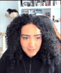 a woman with curly hair is wearing a black sweatshirt